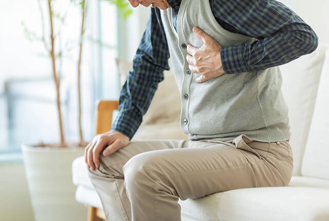 ソファに座り胸を抑える男性