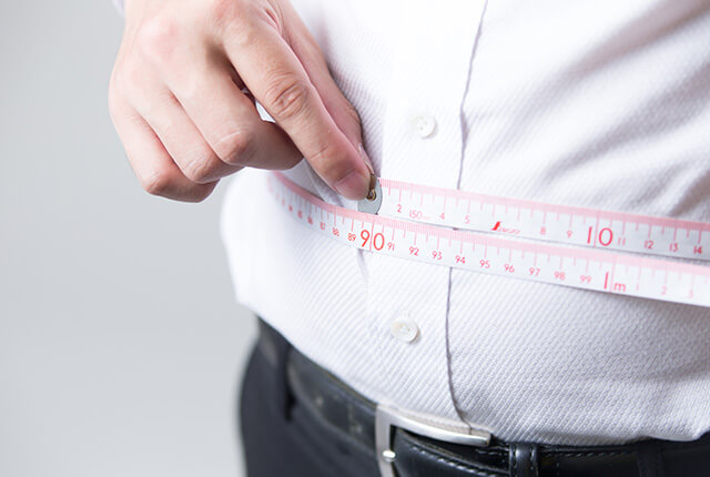 メジャーでお腹周りを測定する中年男性